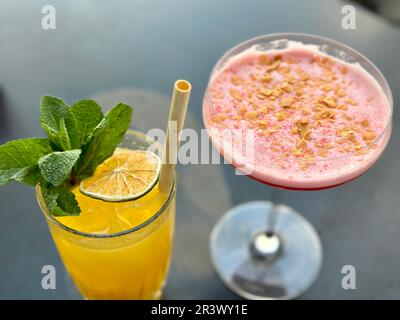 Detox Bio-Diätgetränke, hausgemachte tropische Smoothies - Orange, Grapefruit, in Portionsgläsern, mit Zutaten, auf einem grauen Steintisch. Stockfoto