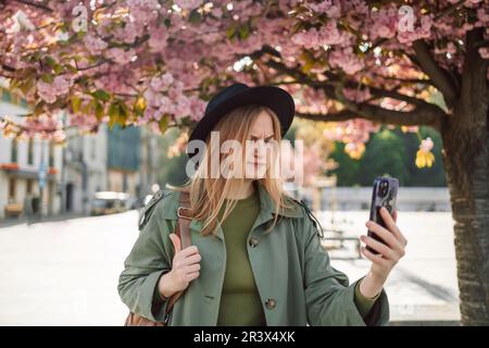 Verärgerte, stilvolle Kleidung blondes Mädchen Tourist reist auf der Suche nach Wegbeschreibungen auf dem Smartphone durch die Altstadt von Krakau in der Nähe des Wawel Stockfoto