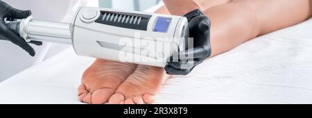 Kosmetologe in Gummihandschuhen bei Endosphären-Therapie an weiblichen Füssen Stockfoto