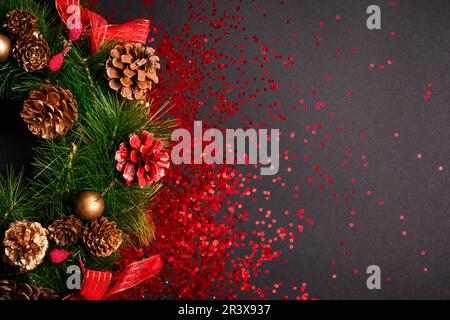 Weihnachtskranz mit rotem Glitzer auf schwarzem Hintergrund, flach liegend mit Kopierfläche Stockfoto