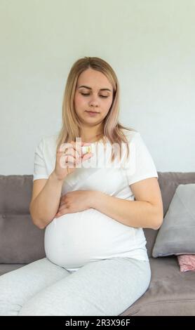 Schwangere Frau trinkt Omega drei. Selektiver Fokus. Weiß. Stockfoto