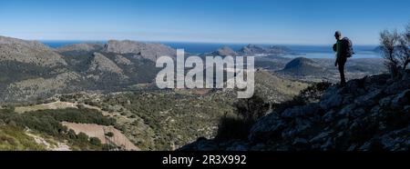 Wanderer steigen auf Cucuia de Fartaritx mit Alcudia Bucht im Hintergrund, Pollença, Mallorca, Balearen, Spanien. Stockfoto