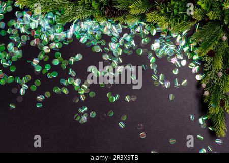 Grünes rundes Konfetti auf schwarzem Papierhintergrund. Flach liegend, Draufsicht Stockfoto