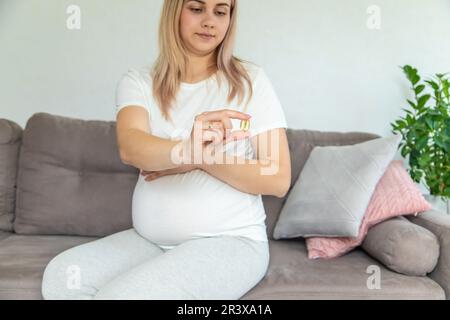 Schwangere Frau trinkt Omega drei. Selektiver Fokus. Weiß. Stockfoto