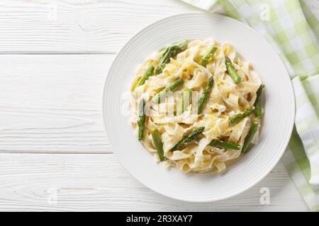 Spargelpastete mit Zitronenschale und Parmesan-Nahaufnahme auf dem Teller auf dem Holztisch. Horizontale Draufsicht von oben Stockfoto