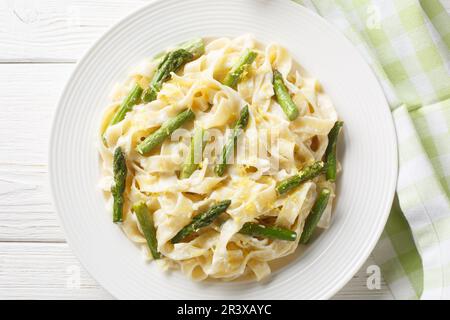 Köstliche Fettuccine Pasta mit Spargel, Zitrone in cremiger Parmesansauce, Nahaufnahme auf einem Teller auf dem Tisch. Horizontale Draufsicht von oben Stockfoto