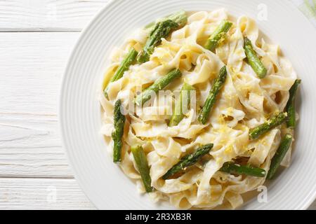 Cremige Zitronencreme Asparagus Pasta fettuccine auf dem Teller auf dem Holztisch. Horizontale Draufsicht von oben Stockfoto