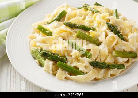 Köstliche Fettuccine Pasta mit Spargel, Zitrone in cremiger Parmesansauce, Nahaufnahme auf einem Teller auf dem Tisch. Horizontal Stockfoto