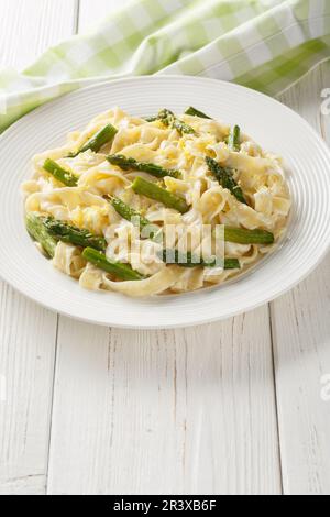 Zitronenspargel Pasta fettuccine mit Parmesan-Sahne-Sauce auf dem Teller auf dem Holztisch. Vertikal Stockfoto