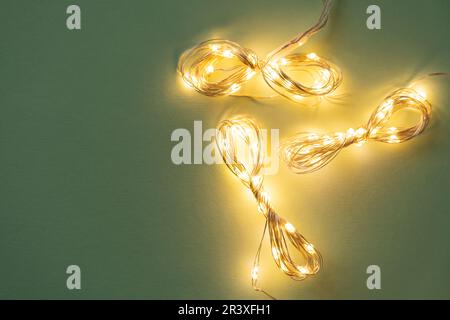Weihnachtsbeleuchtung auf hellgrünem Hintergrund, flach lag mit Ferien-Girlande Stockfoto