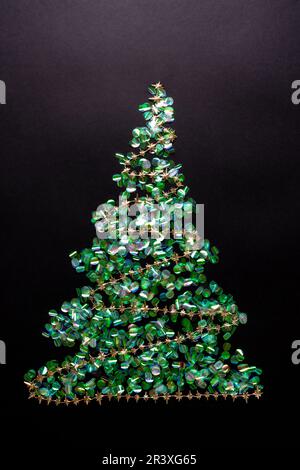 Weihnachtsbaum mit Girlande aus grünem Konfetti auf schwarzem Hintergrund. Neujahrskonzept mit Lametta. Flach liegend, Draufsicht Stockfoto