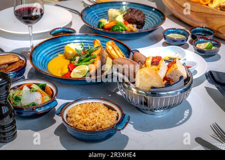 Luxuriöser Banketttisch in einem 5-Sterne-Hotel, es gibt viele attraktive Gerichte: Gegrillte Garnelen, Austern mit Käsesauce, Rinderbitset und gebratener Lachs. Stockfoto