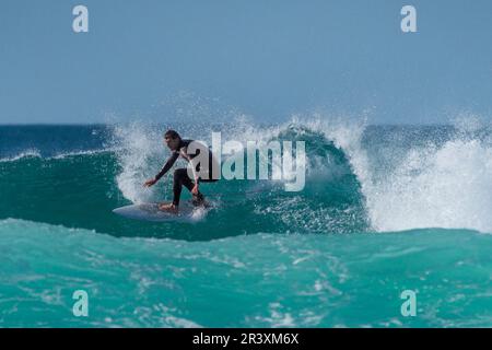 Spektakuläre Surfaktion als männlicher Surfer reitet auf einer Welle im Fistral in Newquay in Cornwall in England in Großbritannien. Stockfoto