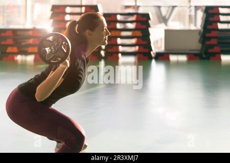 Fitness-, Sport-, Krafttraining- und People-Konzept - sportliche Frau beim Training mit der Barglocke im Fitnessstudio Stockfoto