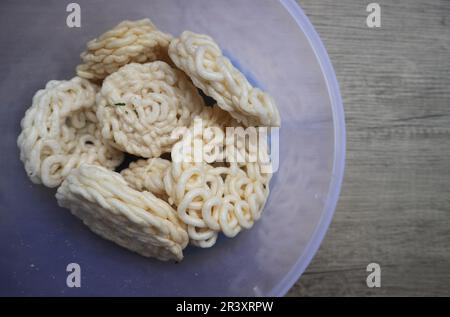 Kerupuk oder Kerupuk Warung sind traditionelle indonesische frittierte Cracker aus Stärke, gemischt mit Aromen wie Fisch, serviert in einem Kunststoffkontuin Stockfoto