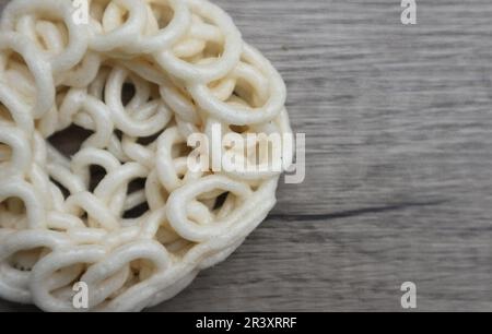 Kerupuk oder Kerupuk Warung sind traditionelle indonesische frittierte Cracker aus Stärke, gemischt mit Aromen wie Fisch, isoliert auf einem Holztisch. Stockfoto