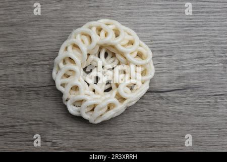 Kerupuk oder Kerupuk Warung sind traditionelle indonesische frittierte Cracker aus Stärke, gemischt mit Aromen wie Fisch, isoliert auf einem Holztisch. Stockfoto