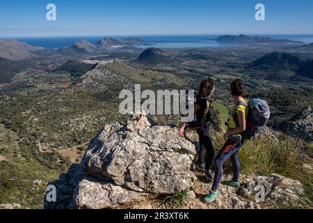 Wanderer steigen auf Cucuia de Fartaritx mit Alcudia Bucht im Hintergrund, Pollença, Mallorca, Balearen, Spanien. Stockfoto