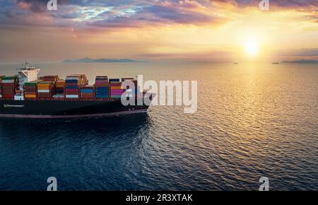 Der Bug eines Containerschiffs auf offenem Meer, das in den Sonnenuntergang segelt Stockfoto