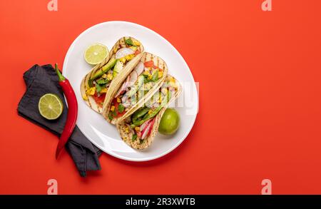 Mexikanische Küche mit Tacos mit Fleisch und gegrilltem Gemüse. Flache Überlagerung in Rot mit Kopierbereich Stockfoto