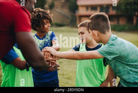 Schulkinder, die sich mit ihrem Trainer auf einem Sportplatz treffen. Das Rugby-Team hält vor dem Üben ein motivierendes Gespräch. Sporttrainer betreut Chil Stockfoto