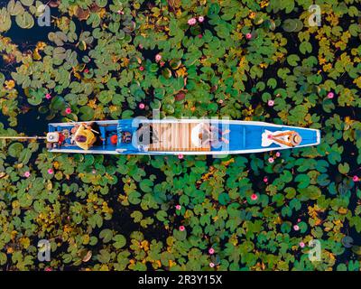 Ein Paar in einem Boot am Roten Lotus See Kumphawapi voller rosa Blumen in Udon Thani Thailand. Stockfoto