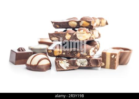 Zerbrochene Schokoriegel mit Nüssen und Pralinen isoliert auf weißem Hintergrund. Stockfoto