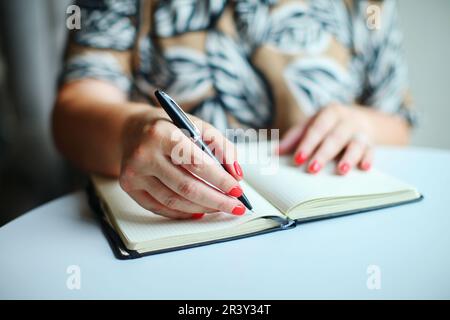 Nahaufnahme von Frauenhänden, die in Notizblock geschrieben haben Stockfoto