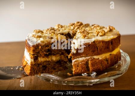 Ein köstlicher Karotten- und Walnusskuchen, der geschnitten wird, hausgemachter Bäcker. Stockfoto