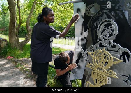 HINWEIS: SPRACHE AUF DER SKULPTUR Marcia Dunkley vom Black Heritage Walks Network und Künstler Luke Perry reinigt rassistische Graffiti von seiner Skulptur, Black British History is British History, am Soho Loop Canal in Winson Green, Birmingham, nachdem es verwüstet wurde. Foto: Donnerstag, 25. Mai 2023. Stockfoto