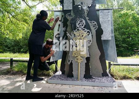 HINWEIS: SPRACHE AUF DER SKULPTUR Marcia Dunkley vom Black Heritage Walks Network und Künstler Luke Perry reinigt rassistische Graffiti von seiner Skulptur, Black British History is British History, am Soho Loop Canal in Winson Green, Birmingham, nachdem es verwüstet wurde. Foto: Donnerstag, 25. Mai 2023. Stockfoto