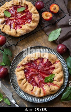 Vegane vegetarische Nachspeise, Pflaumengalette mit Mandeln. Gesunder hausgemachter Vollkornfruchtkuchen, süße Crostata auf einem rustikalen Tisch. Stockfoto