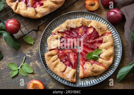 Vegane vegetarische Nachspeise, Pflaumengalette mit Mandeln. Gesunder hausgemachter Vollkornfruchtkuchen, süße Crostata auf einem rustikalen Tisch. Stockfoto