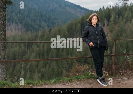 Porträt einer jungen, süßen, attraktiven Reisenden, die in einem Bergtal reist. Glückliches Mädchen, Tourist posiert auf dem Gipfel des Berges. Trav Stockfoto