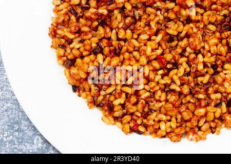 Getreidekörner nach spanischer Art, Reis, roter Pfeffer und Tomatenpaste Stockfoto