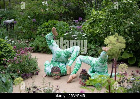 BILDER ABLEGEN. 25. Mai 2023. Die Gruppe der Öko-Aktivisten Just Stop Oil hat heute auf der Chelsea Flower Show, entworfen von Paul Hervey-Brookes, orangefarbene Farbe auf den RBC Brewin Dolphin Garden gesprüht (Bilder zeigen Künstler im Garten am Press Day am Montag Anfang dieser Woche). Pimlico, London, Großbritannien. 22. Mai 2023. Ein Paar darstellender Schlangenmenschen führt eine Interpretation durch, die den Wissenstransfer durch eine stufenweise Bewegung darstellt, wobei das Thema des Gartens aufgegriffen wird. Kredit: Maureen McLean/Alamy Live News Stockfoto