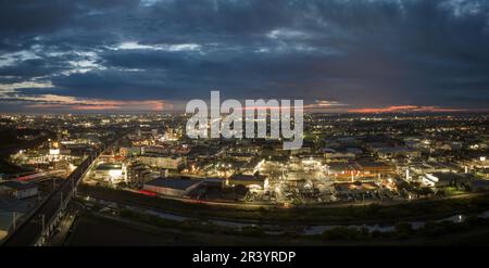 Panoramablick aus der Vogelperspektive auf die erhöhten Bahngleise und die Lichter der Stadt nach Sonnenuntergang Stockfoto