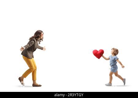 Ein kleines Mädchen, das ein rotes Herz hält und auf eine junge Frau zuläuft, isoliert auf weißem Hintergrund Stockfoto