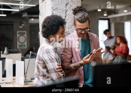 Lächelnd treffen sich verschiedene Kollegen in einem Brainstorming in der Vorstandsetage, um gemeinsam Finanzstatistiken zu diskutieren Stockfoto