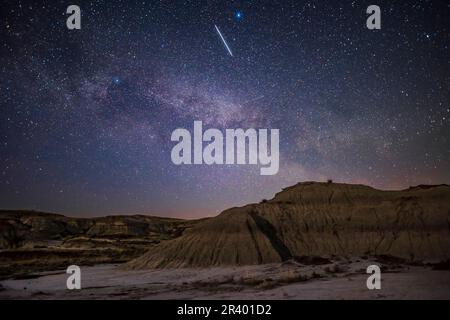 Ein Zug von Starlink-Satelliten bewegt sich in östlicher Richtung über die Mondlandschaft des Dinosaur Provincial Park, Alberta, Kanada. Stockfoto