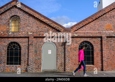 Sandnes, Rogaland, Norwegen, 18 2023. Mai, ein Mann in farbenfroher Sportkleidung, der an Einem traditionellen Backsteingebäude in Downtown Sandnes in Even vorbeigeht Stockfoto