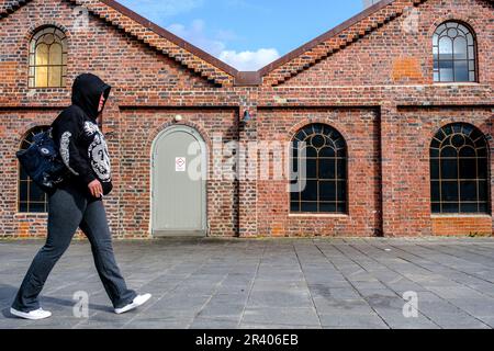 Sandnes, Rogaland, Norwegen, Mai 18 2023, Teenage Boy Trägt Schwarzen Hoodie Und Rucksack, Der Am Traditionellen Backsteingebäude Vorbeigeht Stockfoto