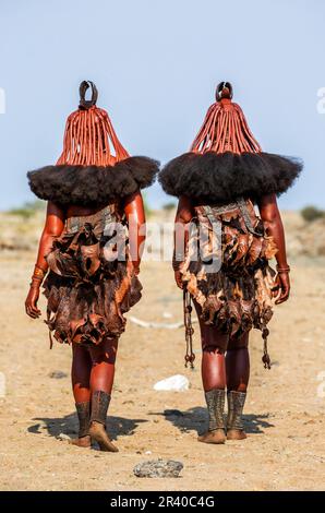 Zwei Frauen des Himba-Stammes laufen in Nationalkleidung durch die Wüste. Stockfoto