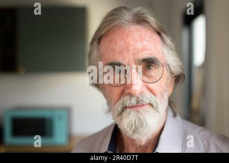 Glücklicher Senior-Mann mit Brille, der sich ein Kameraporträt ansieht Stockfoto