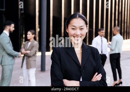 Porträt einer gut aussehenden, erfolgreichen Führungskraft, die mit gekreuzten Armen lächelt. Attraktive junge Geschäftsfrau, die selbstbewusst in die Kamera schaut Stockfoto