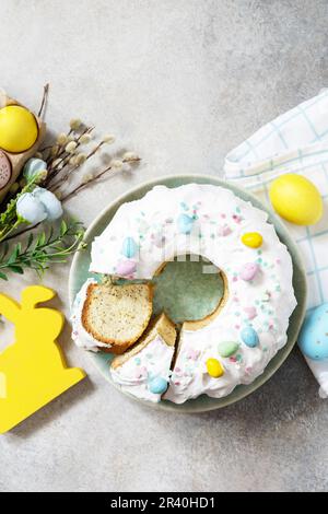 Frohe Osterferien, leckeres Dessert. Glasierter osterzitronenkuchen mit Süßwaren und Mini-Schokoladeneiern, Süßigkeiten auf Gras Stockfoto