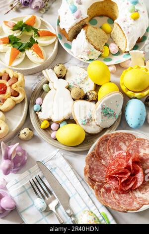 Festliches Abendessen, Osterbrunch. Ostertisch mit einer Auswahl an Backwaren, Desserts, gefüllten Eiern und gefärbten Eiern auf einem Marmor Stockfoto