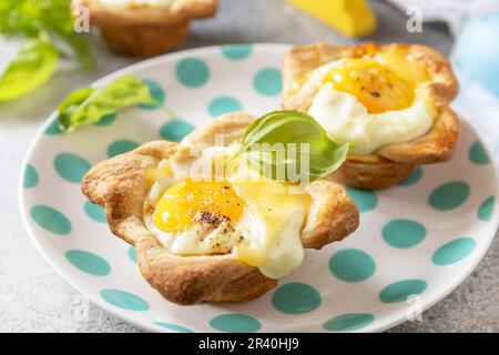 Osterfrühstück-Idee. Rührei in Blätterteig mit Käse und Speck auf einem Steinhintergrund. Stockfoto