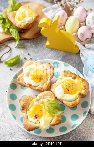 Osterfrühstück-Idee. Rührei in Blätterteig mit Käse und Speck auf einem Steinhintergrund. Stockfoto