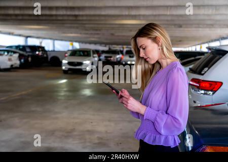 Eine hübsche blonde Assistentin geht nach Einem langen Tag auf Einem überdachten Parkplatz zu ihrem Auto Stockfoto